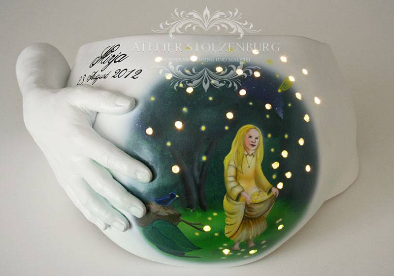 Weißer Babybauch mit der Hand der Mutter auf dem Bauch ist das Motiv der Sterntaler, die Taler werden von leuchtenden LEDs dargestellt.
