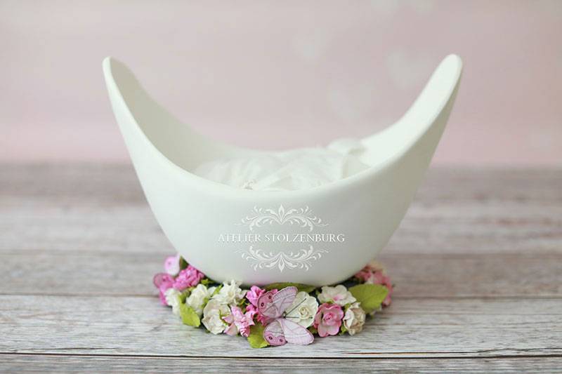 Eine schlichte weiße Belly Bowl auf einem Styropor-Ring, der mit Blumen verziert wurde.
