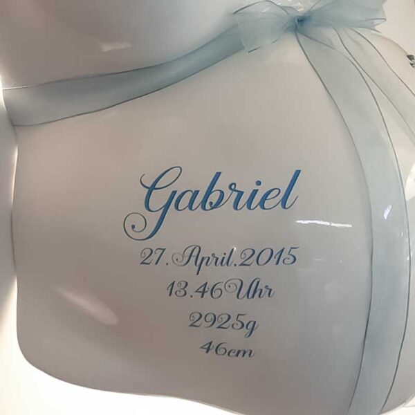 Name und Geburtsdaten auf einem weißen Babybauchabdruck