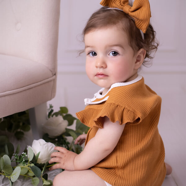 Kinderfotografie im Atelier Karlsruhe mit dezenten Blumen-Elementen am Set, Fokus auf dem Kind.