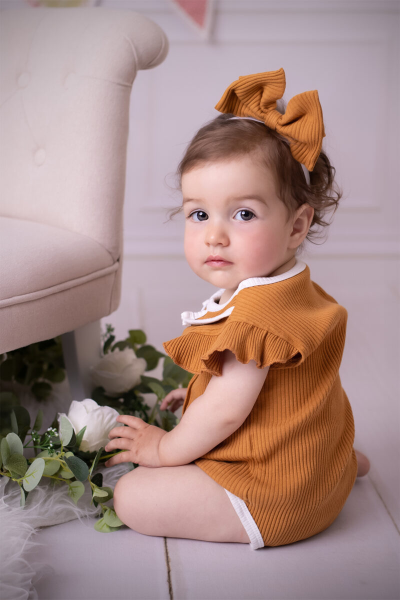 Kinderfotografie im Atelier Karlsruhe mit dezenten Blumen-Elementen am Set, Fokus auf dem Kind.
