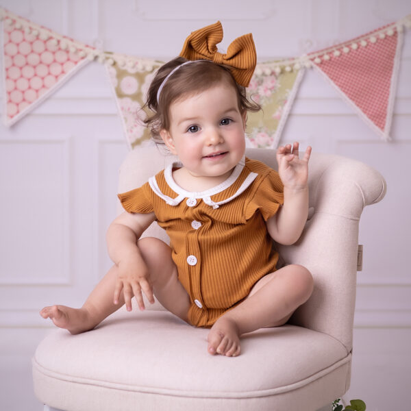 Kind sitzt entspannt auf einem kleinen Sessel im Fotostudio in Karlsruhe, natürliche Pose und ruhiger Blick.