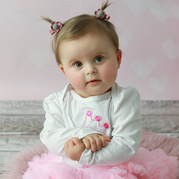 Geburtstagskind mit Schleifen im Haar und rosa Tüllrock beim Fotoshooting im Studio