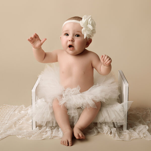 Baby sitzt im Studio und macht eine kleine Handbewegung, Sitter Session.
