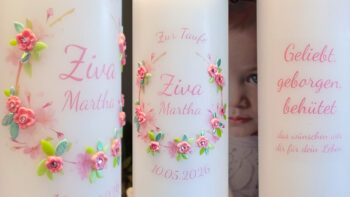 Collage einer personalisierten Taufkerze mit Blumenkranz in Rosa und Grün, Name „Ziva Martha“ und Spruch „Geliebt, geborgen, behütet“ sowie rosafarbenem Kerzenband.