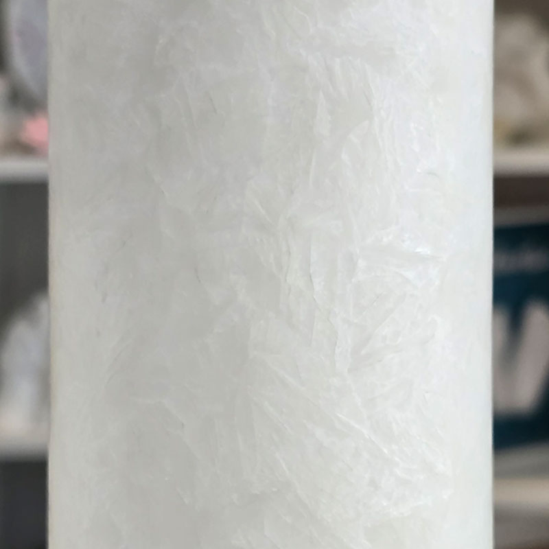Detailansicht der rustikalen Oberfläche einer weißen Kerze mit Teelichteinsatz, glatt genug zum Verzieren mit Kerzenfolie und Wachsdeko.