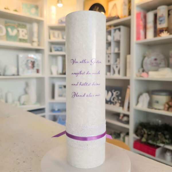 Rückseite einer weißen Taufkerze mit violettem Taufspruch „Von allen Seiten umgibst du mich und hältst deine Hand über mir“ und violettem Band.