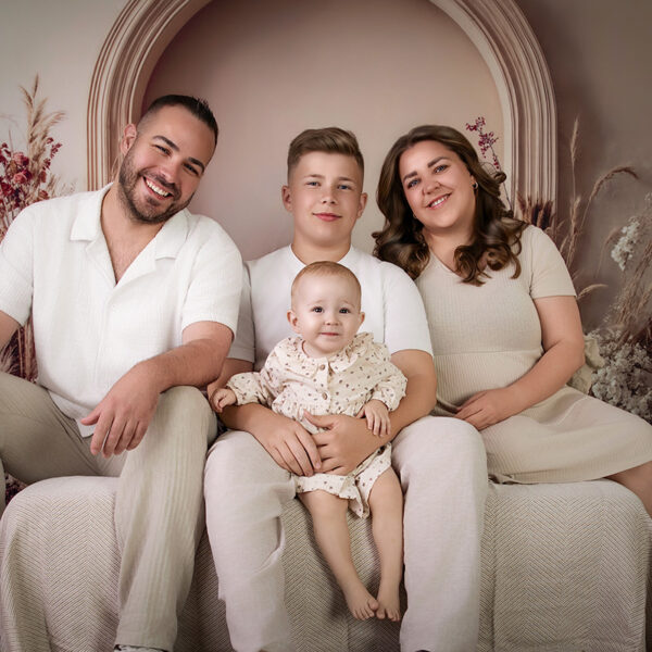 Herzliches Familienfoto mit glücklich lachendem Baby auf dem Schoß des Bruders im Boho-Atelier in Karlsruhe