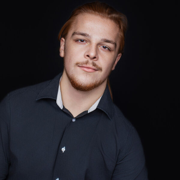 Nahaufnahme Charakterporträt eines jungen Mannes mit Bart vor dunklem Hintergrund fotografiert im Fotostudio Karlsruhe