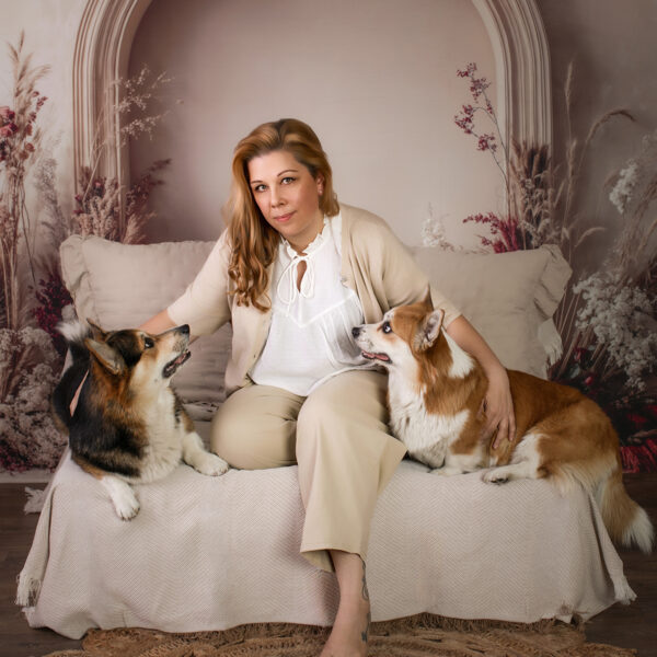 Zeitloses Porträt von Frau und ihren beiden Hunden auf hellem Sofa im gemütlichen Boho-Fotostudio.