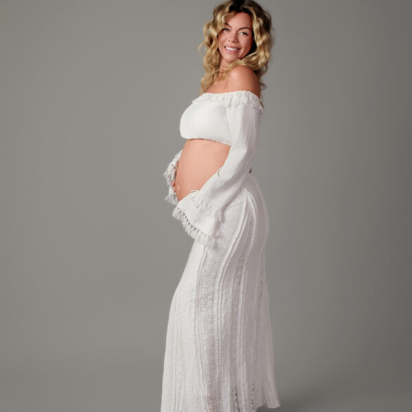 Wunderschönes, helles Outfit: Schwangere Frau posiert in weißer Spitzenkleidung im Atelier Stolzenburg.